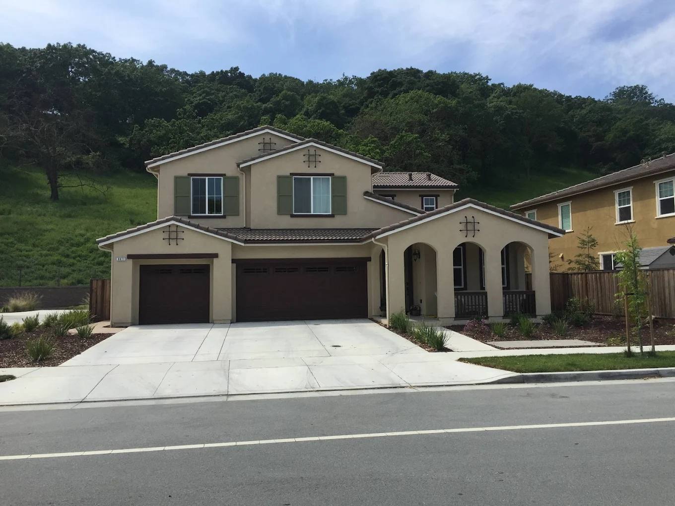 Cream stucco two-story home with a three-car garage, freshly painted