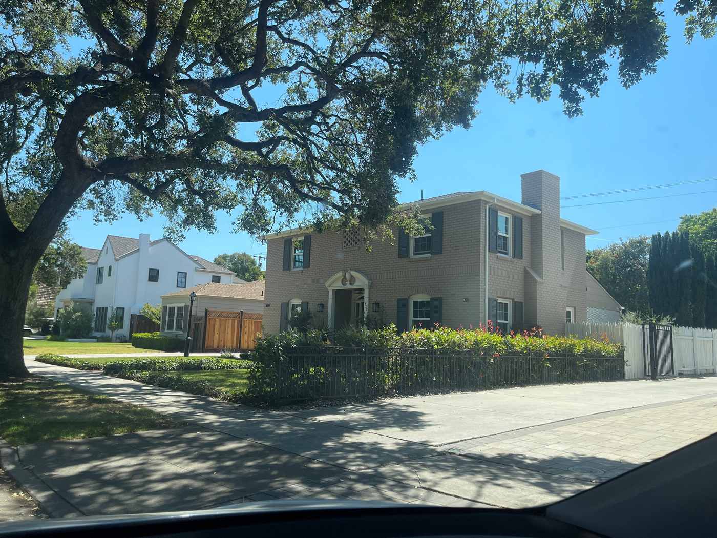 Two-story home on a corner lot under an oak after exterior painting