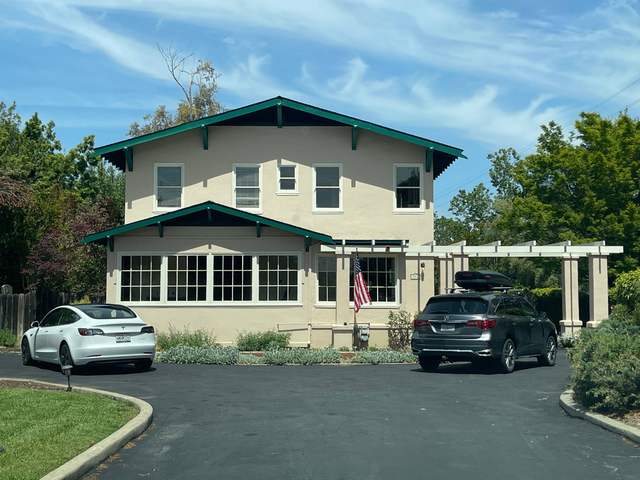 White two-story home with green trim and a painted pergola